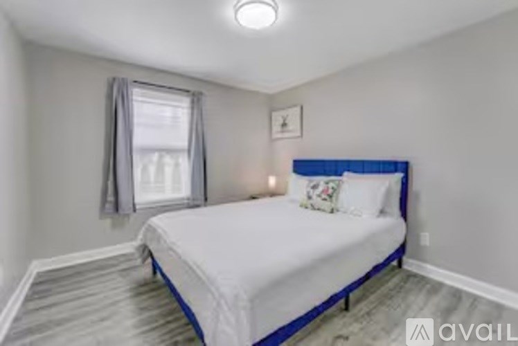 A bedroom with a bed, a window with curtains, and a picture on the wall.