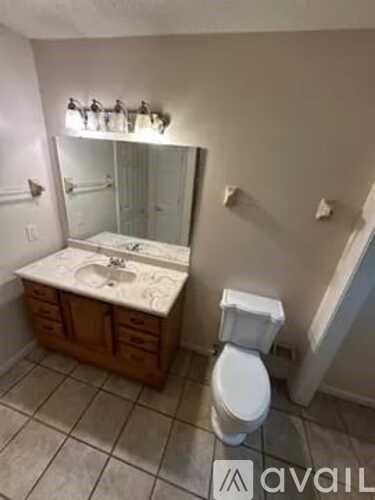 A bathroom with a toilet, sink, and mirror.