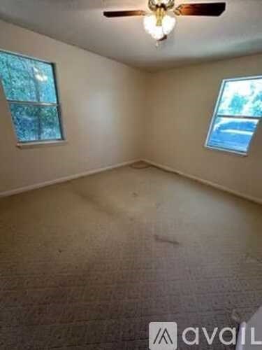 A room with a ceiling fan and two windows.