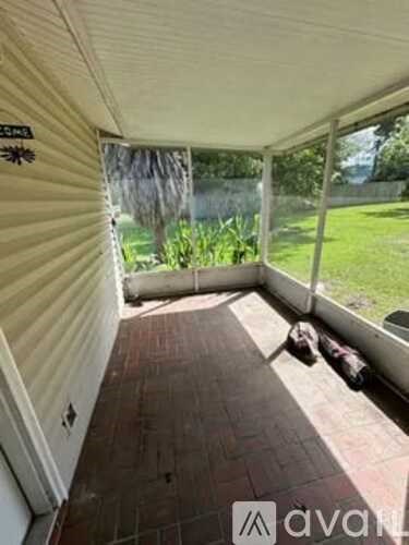 A patio area with a brick floor and a sliding glass door leading to a green lawn.
