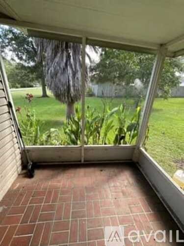 A patio with a view of a green lawn and trees.