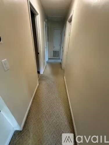 A hallway with a carpeted floor and white walls.