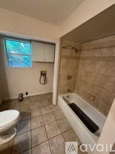 A bathroom with a toilet, tub, and window.