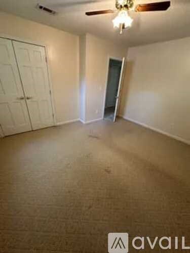 A room with a carpeted floor and a ceiling fan.