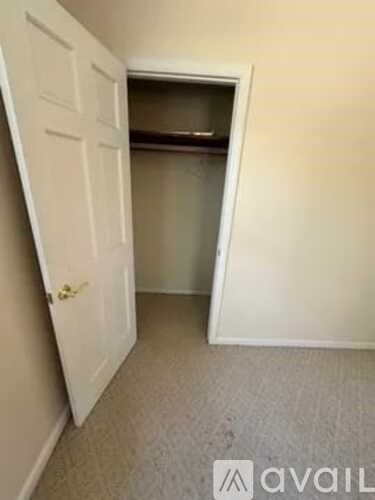 A white door is open to a small, empty room with a carpeted floor.