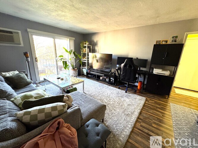 A living room with a grey couch and a black bookshelf.