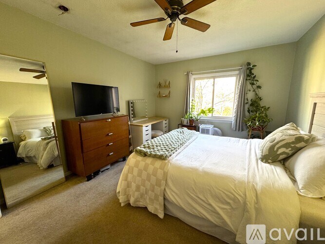 A bedroom with a bed, dresser, and television.