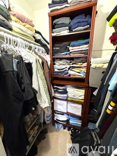 A room with a lot of clothes on shelves and hanging on a rack.