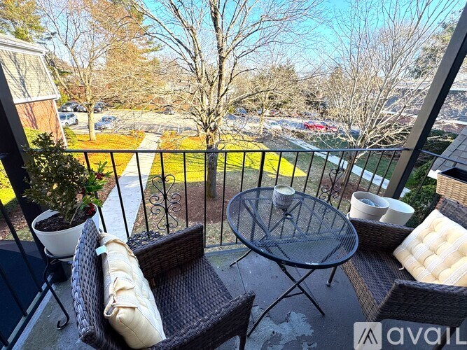 A balcony with a table and chairs overlooking a parking lot.