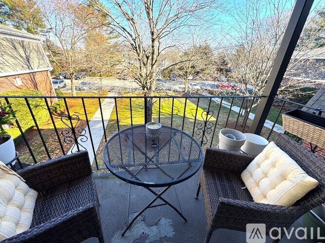 A balcony with a table and chairs overlooking a parking lot.