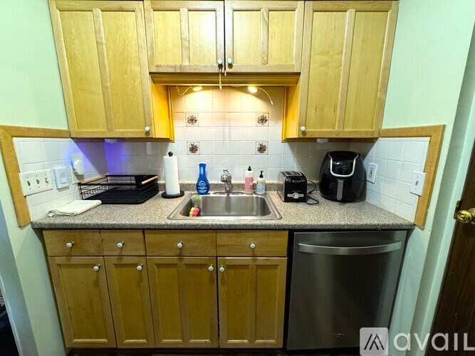 A kitchen with wooden cabinets and a stainless steel dishwasher.