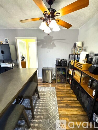 A room with a ceiling fan and a long wooden table.