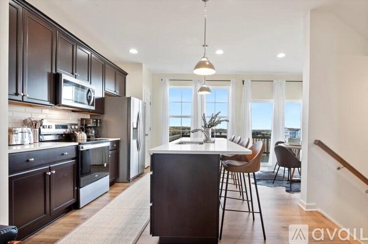 A kitchen with dark brown cabinets and a black island.