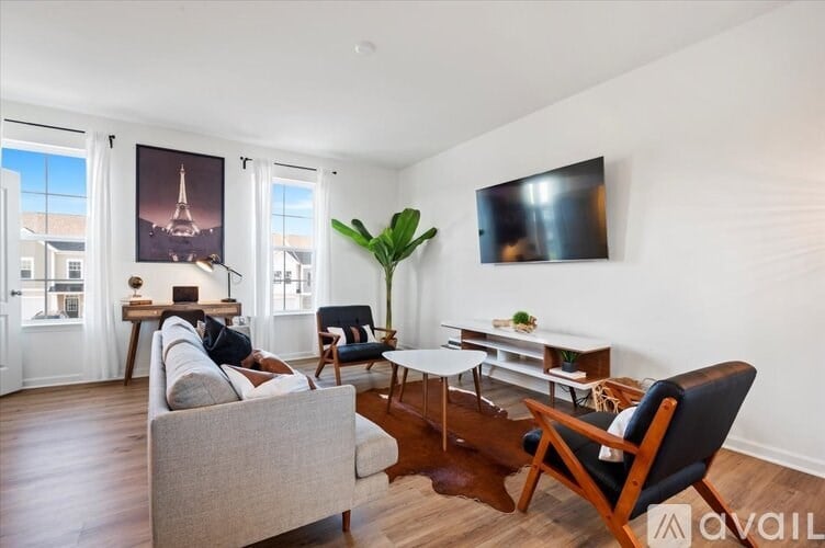 A living room with a grey couch, a wooden coffee table, and a flat screen TV mounted on the wall.