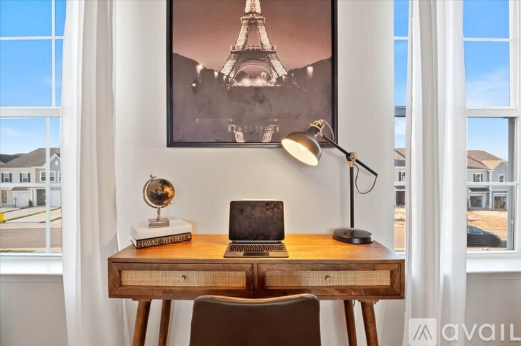 A desk with a laptop, a lamp, and a globe on it with a picture of the Eiffel Tower in the background.