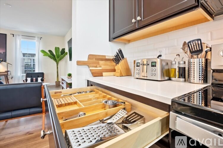 A kitchen with a wooden drawer organizer and a black chair.