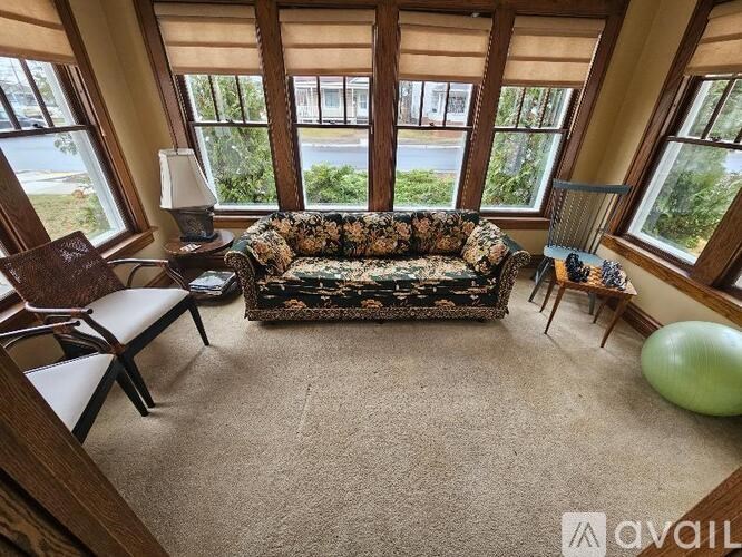 A living room with a couch, chairs, and a lamp.