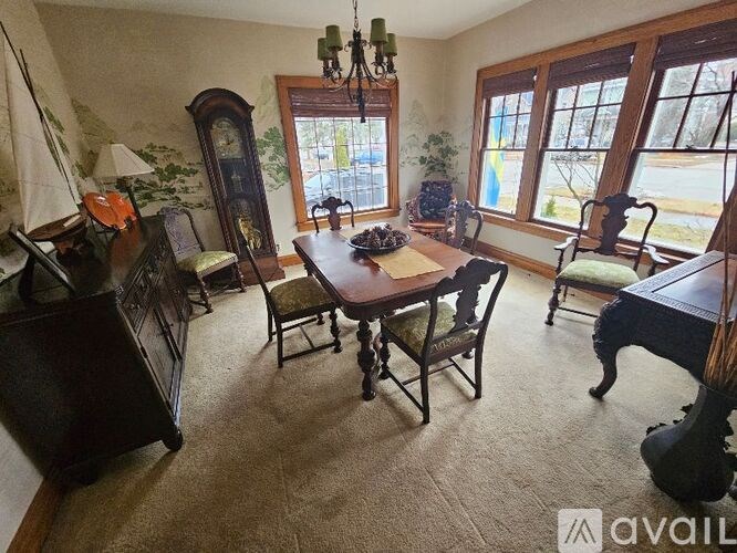 A room with a piano, a table, chairs, and a chandelier.
