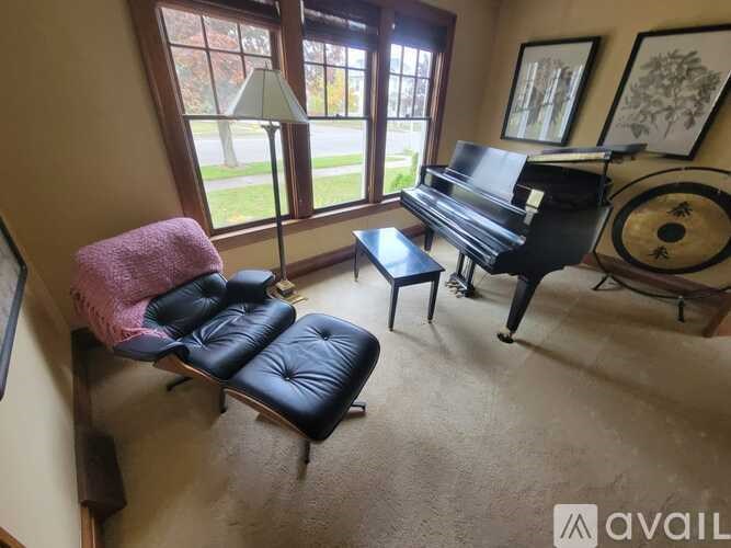 A living room with a piano, chair, and lamp.