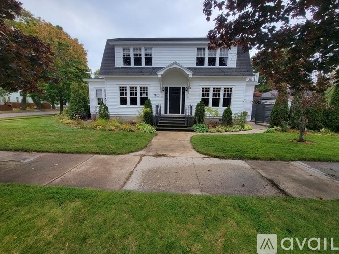 A white house with a black roof and a front porch.