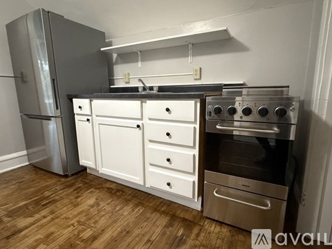 A kitchen with a stainless steel refrigerator, a white drawer unit, and a stainless steel oven with four pans in it.