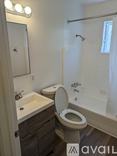 A bathroom with a toilet, sink, and mirror.