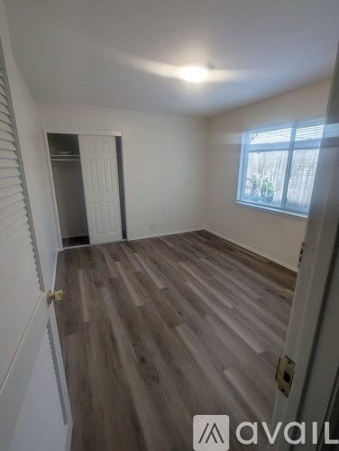 A room with wooden flooring and a window with blinds.