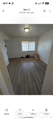 A room with wooden flooring and a window with blinds.