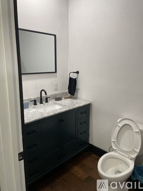 A bathroom with a toilet, sink, and mirror.