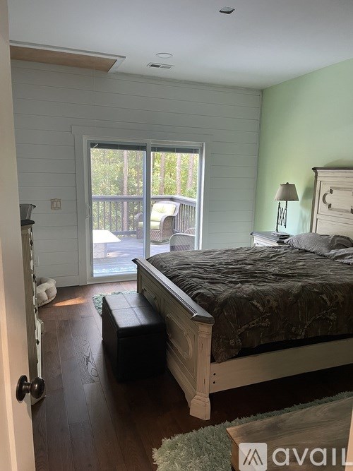 A bedroom with a bed, bench, and sliding glass doors.
