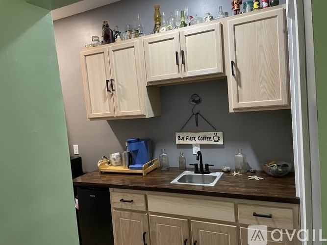 A kitchen with wooden cabinets and a sign that says "But first, coffee".