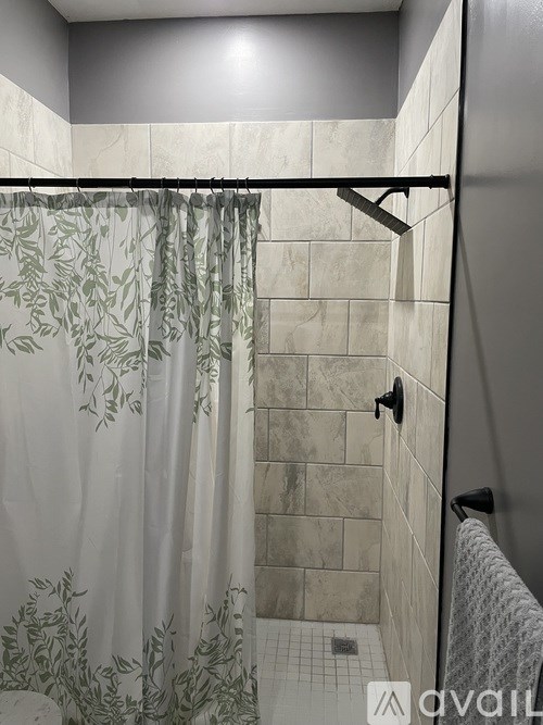 A bathroom with a shower curtain and a shower head.