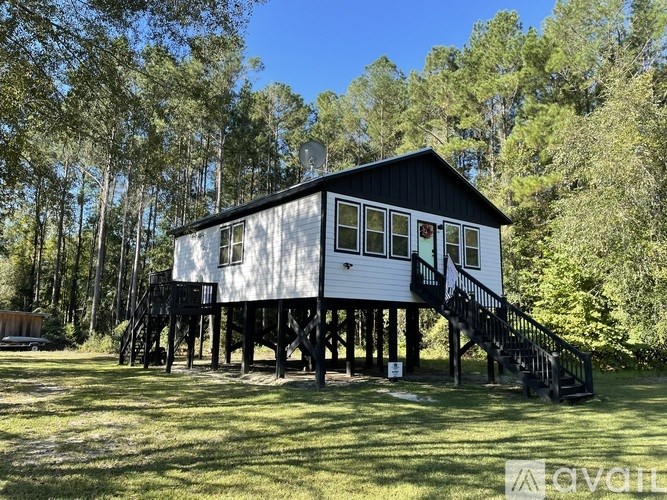 A white and black house with a balcony and stairs leading to the second floor.