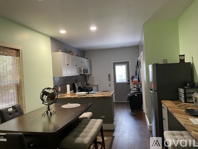 A kitchen with a table and chairs in the foreground and a refrigerator in the background.