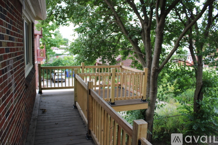 A wooden deck with a railing and trees in the background.