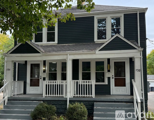 A two-story house with a white porch and a brown door.