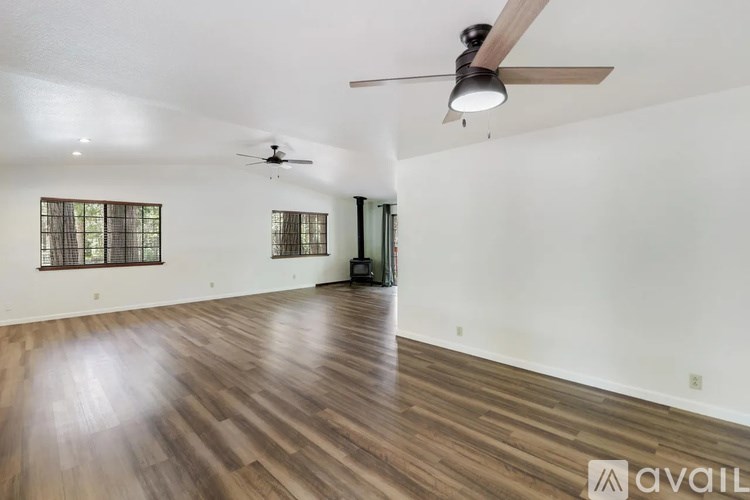 A spacious room with wooden flooring and a ceiling fan.