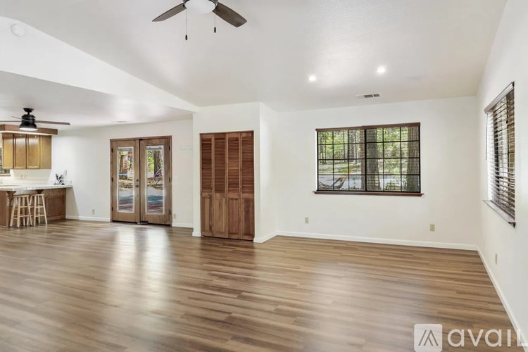 A spacious room with wooden floors and a ceiling fan.