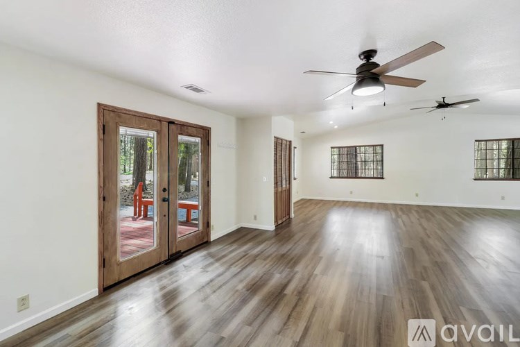 A spacious room with wood flooring and a ceiling fan.