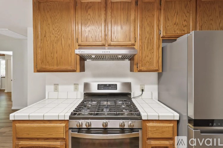 A kitchen with wooden cabinets and a stove top oven.