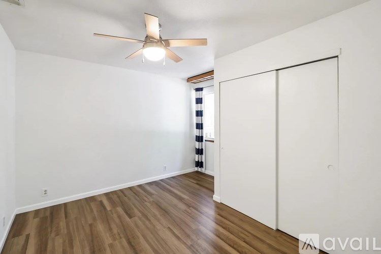 A room with a ceiling fan and wooden flooring.