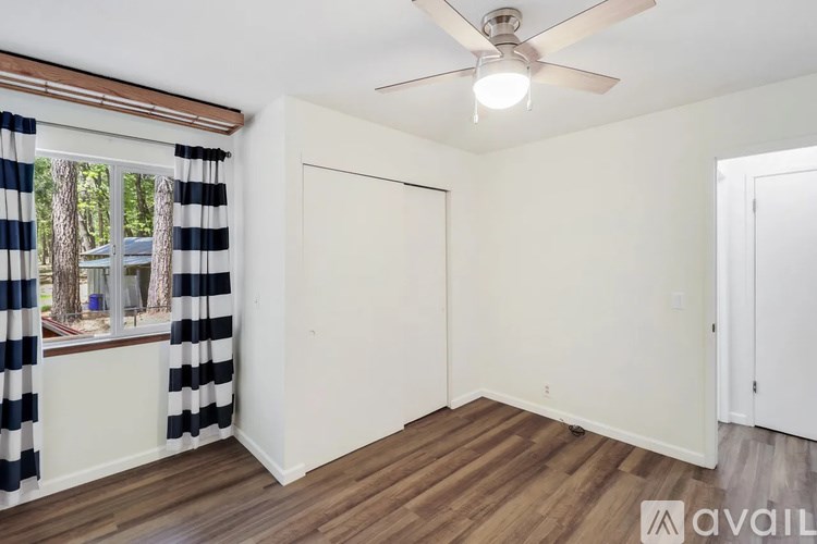 A room with a ceiling fan and a window with striped curtains.