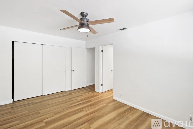 A room with a ceiling fan and wooden flooring.