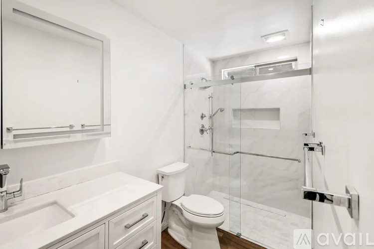 A white bathroom with a toilet, sink, and shower.