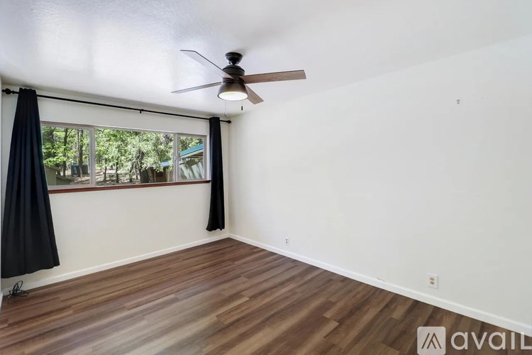 A room with a ceiling fan and a window with black curtains.