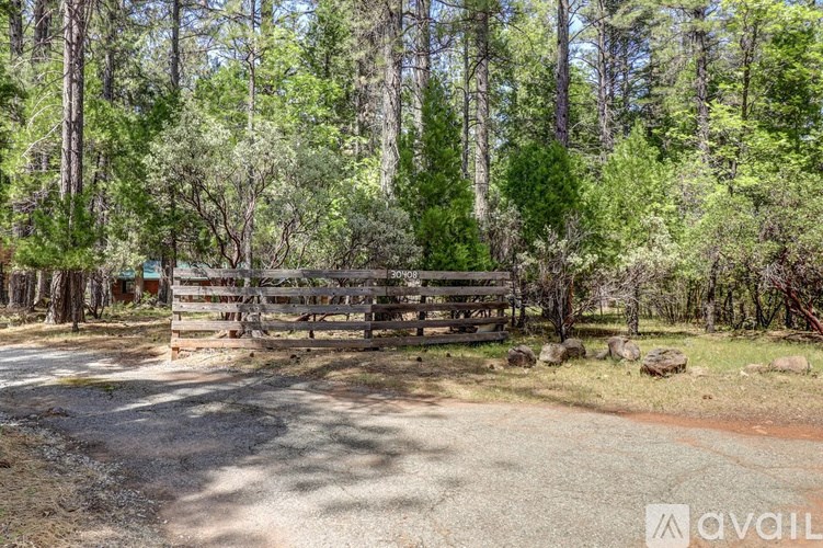 A wooden gate blocks the road in a wooded area.
