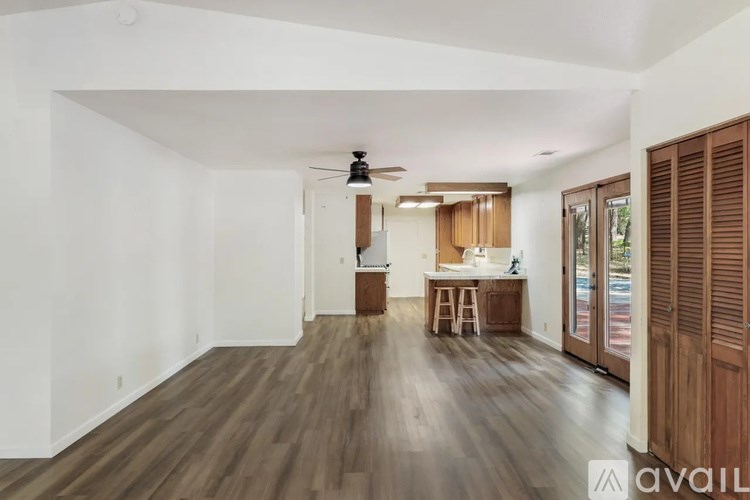 A spacious room with wooden flooring and a ceiling fan.
