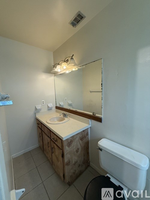 A bathroom with a sink, mirror, and toilet.