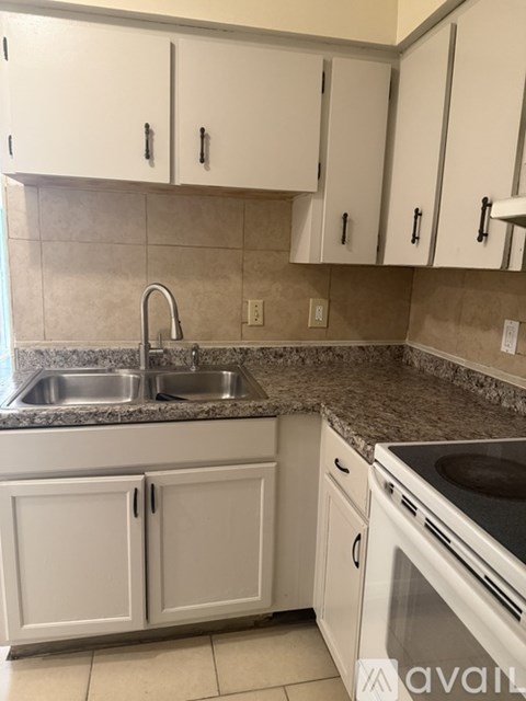A kitchen with white cabinets and a granite countertop.