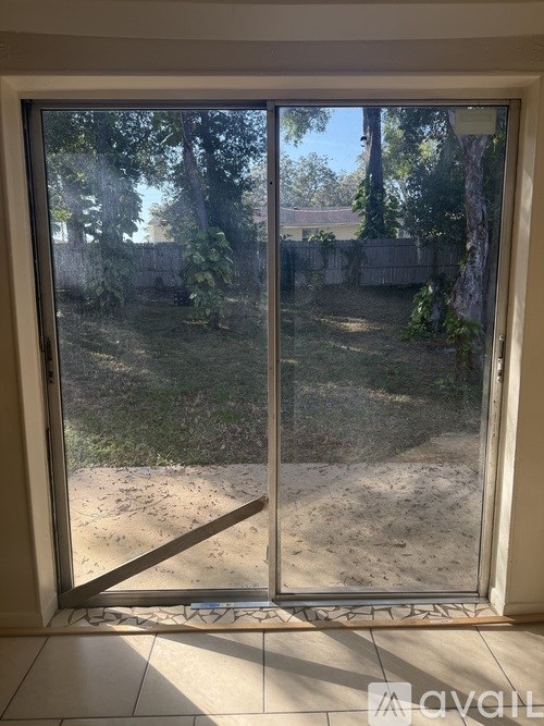 A glass door with a handle and a view of a backyard.